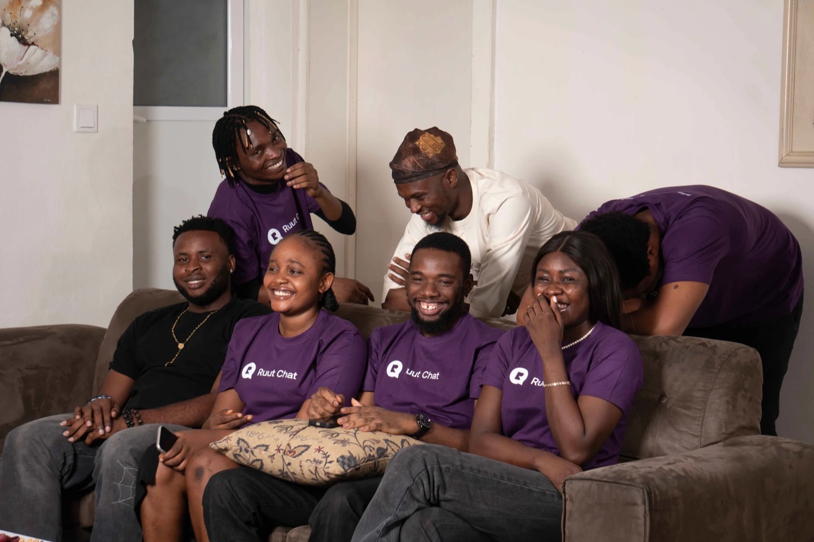 The Ruut team laughing together on a sofa in their purple Ruut Chat t-shirts